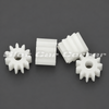 Four Scaleauto SC-1011 white 11-tooth polyamide pinions, front and side views on a dark gray background